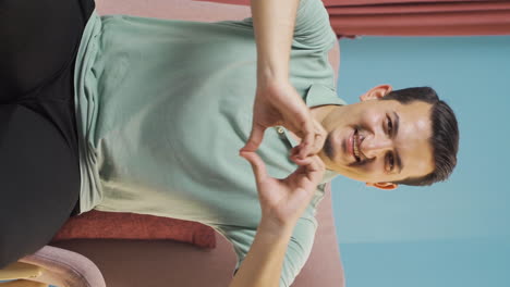 Vertical-video-of-Man-making-heart-symbol-for-camera.